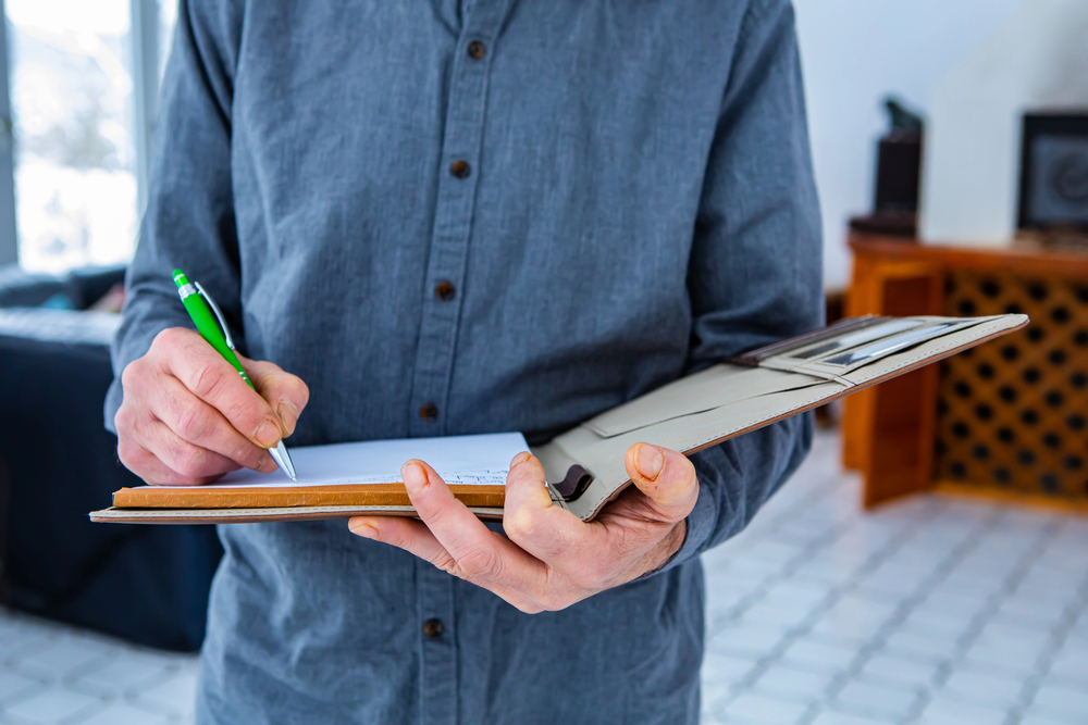 Standing man writes on notebook